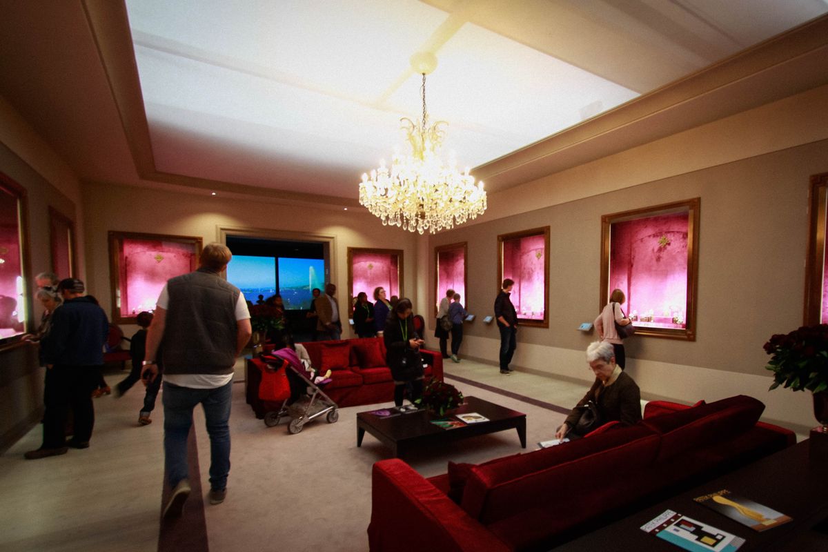The finished salon at the Patek Philippe exhibition, Saatchi Gallery, with chandelier, red sofas and display cases